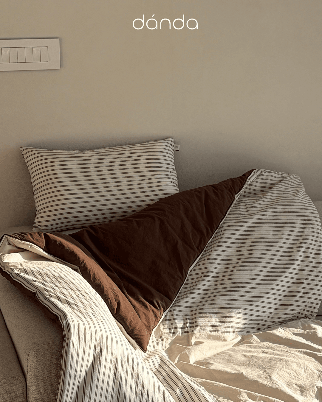 A cozy bedroom with soft striped bedding
